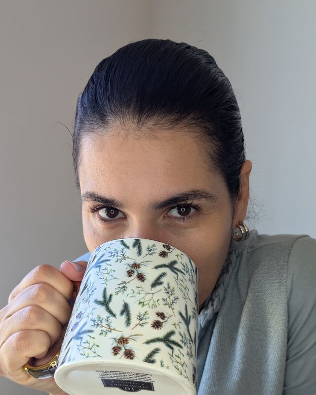 Roberta smiling while holding a mug of coffee